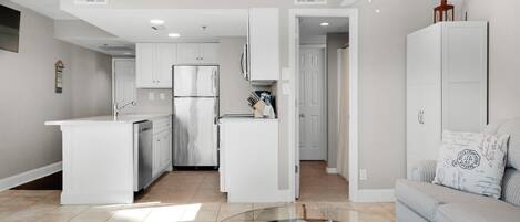 A modern kitchen with white cabinetry, a glass island, and a ceiling fan.