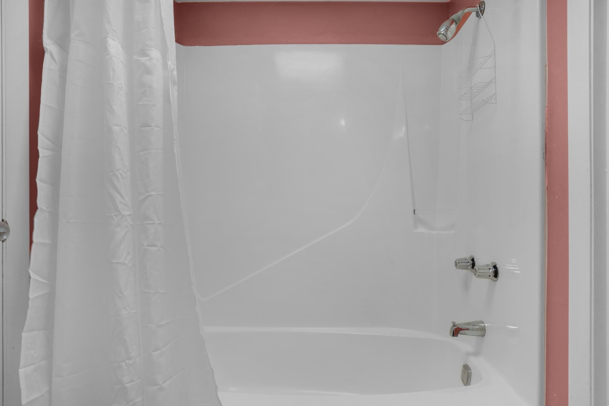 Eine weiße Badewanne mit Duschkopf und zwei Wasserhähnen.