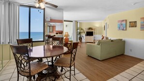 A spacious living area with a dining table, chairs, a sofa, and a ceiling fan. - Sunbird 906w (Panama City Beach)