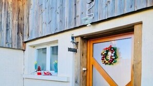 Une façade en bois avec une porte, un banc et une petite décoration de Noël.