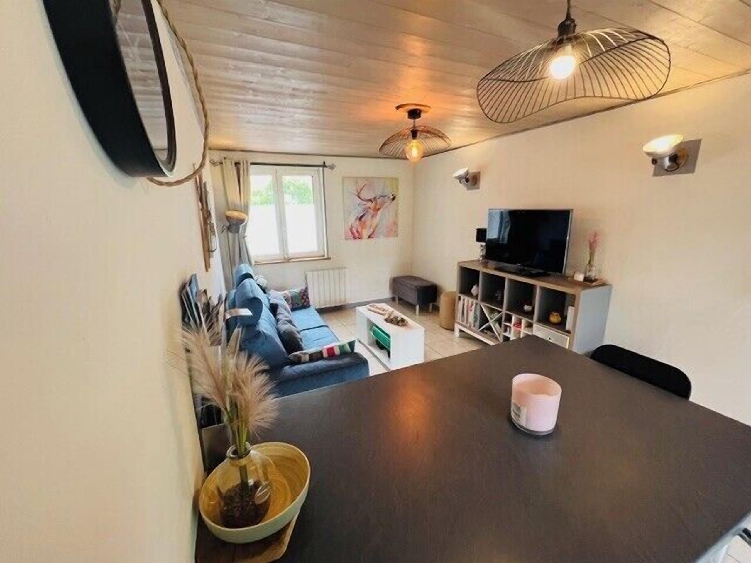 Un salon chaleureux avec une table en bois foncé, un canapé bleu, un téléviseur et un ventilateur de plafond.