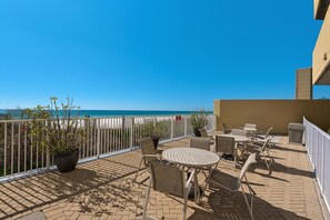 Enjoy ocean views from this outdoor patio with comfortable seating and lush greenery.