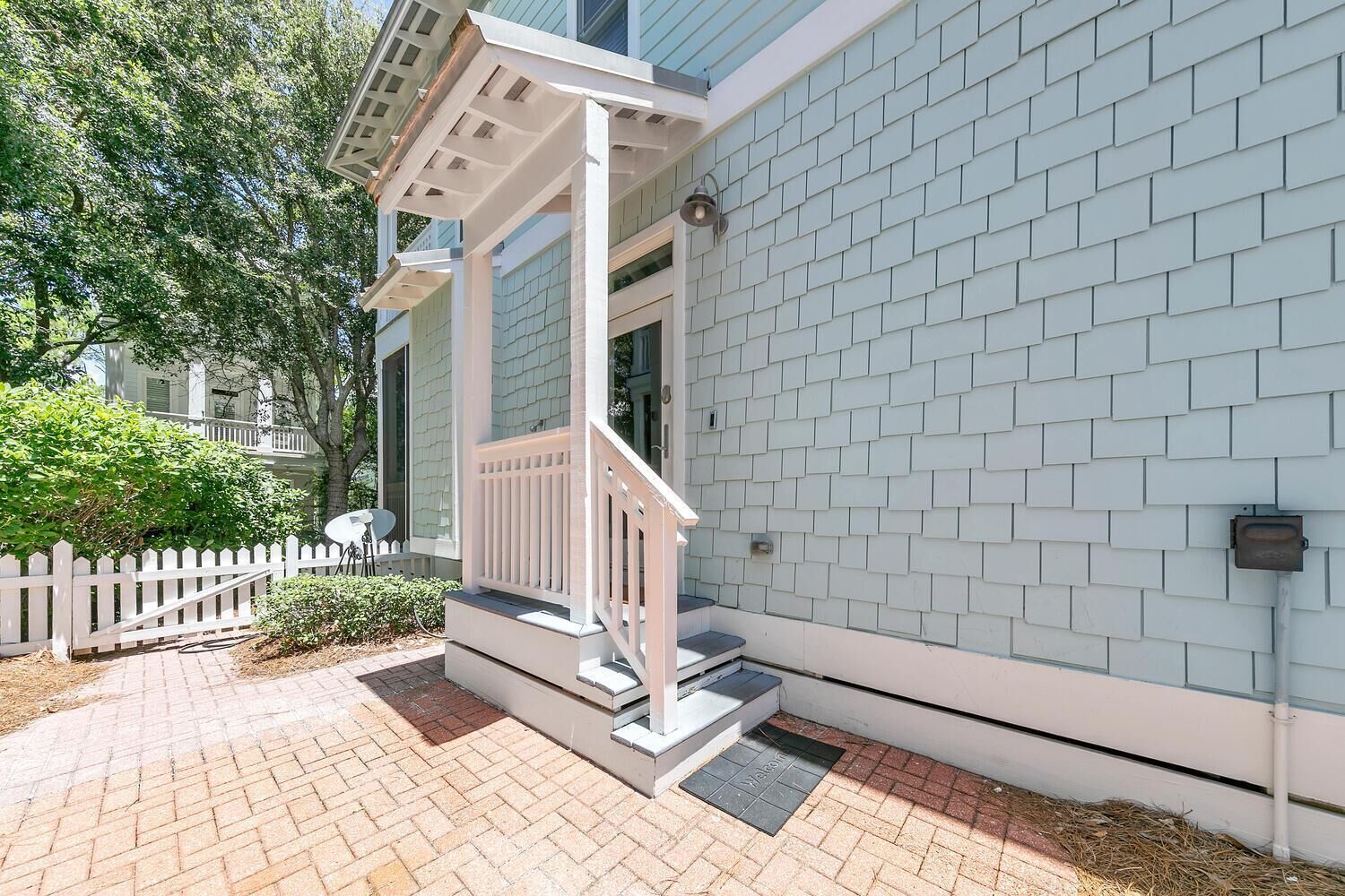 A residential building with a white exterior, a covered porch, and a brick pathway.