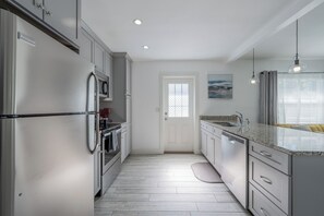 A modern kitchen with stainless steel appliances, a granite countertop, and a view of the outdoors through a window. - Cozy 2BR Apartment in Riverside/ Avondale (Jacksonville)