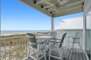 Eine überdachte Terrasse mit Tisch und Stühlen mit Blick auf einen Strand.