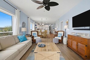 A living room with a sofa, coffee table, and dining area. - Riviera Dunes 203 (Pensacola)