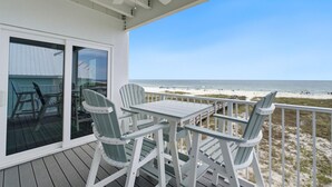 A covered deck with a table and chairs, overlooking a beach. - Riviera Dunes 203 (Pensacola)