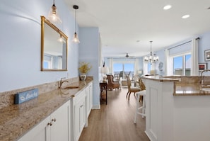 A spacious kitchen with granite countertops, white cabinetry, and pendant lighting. - Riviera Dunes 203 (Pensacola)