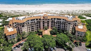 Un grand hôtel à plusieurs étages, doté d’un toit incurvé, entouré de palmiers et offrant une vue sur la plage.
