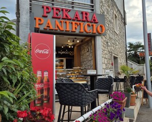 Una cafetería llamada Pekara Panificio con terraza y un anuncio de Coca-Cola.