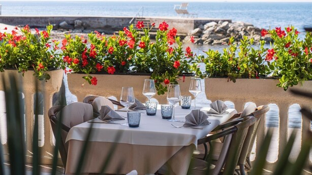 Un área de comedor al aire libre con una mesa preparada para dos, con vista al mar.
