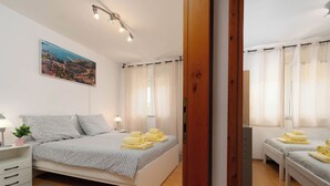 Un dormitorio con una cama, mesitas de noche, una lámpara, una ventana con cortinas y un cuadro en la pared.