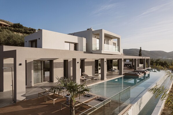 Uma casa moderna com piscina, grandes janelas e varanda.