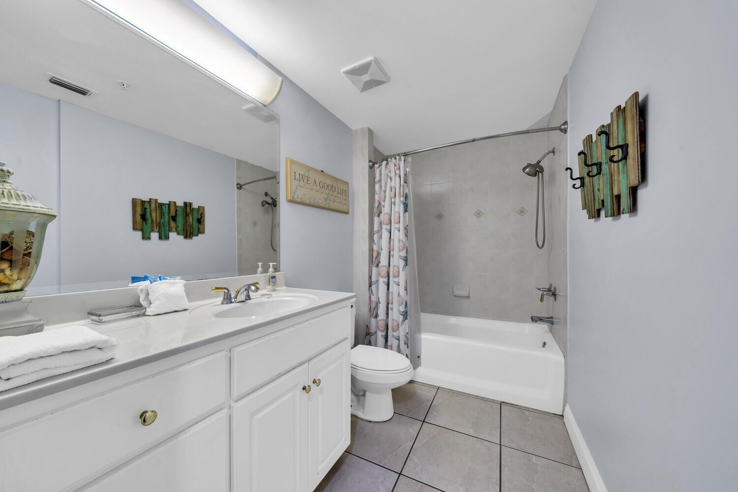 A bathroom with a white vanity, a large mirror, a shower with a glass door, and a toilet.