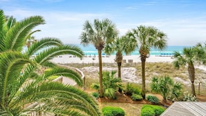 A beach view with palm trees and a wooden deck. - Hidden Dunes 203 (Panama City Beach)