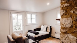 Une pièce confortable avec un lit, une chaise et un mur en pierre.