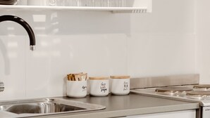 Une cuisine avec des armoires blanches, un évier en acier inoxydable et trois bocaux portant des étiquettes écrites à la main.