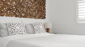 A neatly made bed with white bedding and two pillows with a woven pattern. - The Dog House Cottage (Port Fairy)