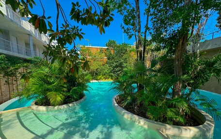 A pool area with two curved water features surrounded by lush greenery and trees.