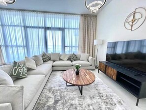 Relax in this stylish living room with a large L-shaped sofa, flat-screen TV, and floor lamp.
