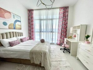 Cozy retreat with a large bed, desk, and chair, perfect for work or relaxation.