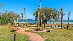 Un parque con mesas de picnic, bancos y un sendero pavimentado.