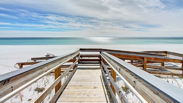A wooden boardwalk leading to a beach with a clear sky and calm sea. - Blue Turtle Dreams (Destin)
