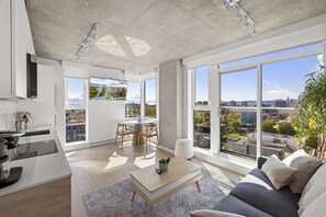 A modern apartment with a kitchen, dining area, and living room, featuring large windows with city views.