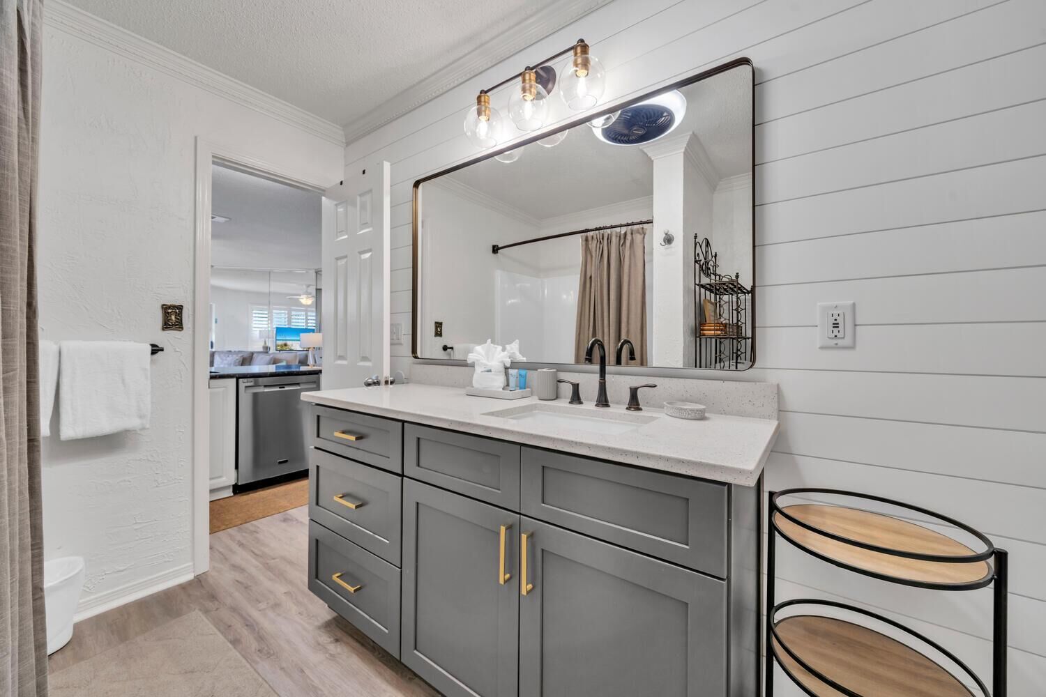 A modern bathroom with a large mirror, grey cabinets, and a white countertop.