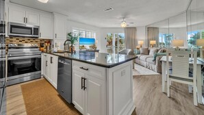 A modern kitchen with stainless steel appliances, a central island, and a view of the outdoors. - Gulfview II 218 (Miramar Beach)