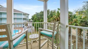 A balcony with a pool view, white railings, and a small table with chairs. - Gulfview II 218 (Miramar Beach)