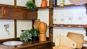 Una encimera de cocina con un lavabo, una tabla de cortar de madera, un cuchillo y una planta en maceta.