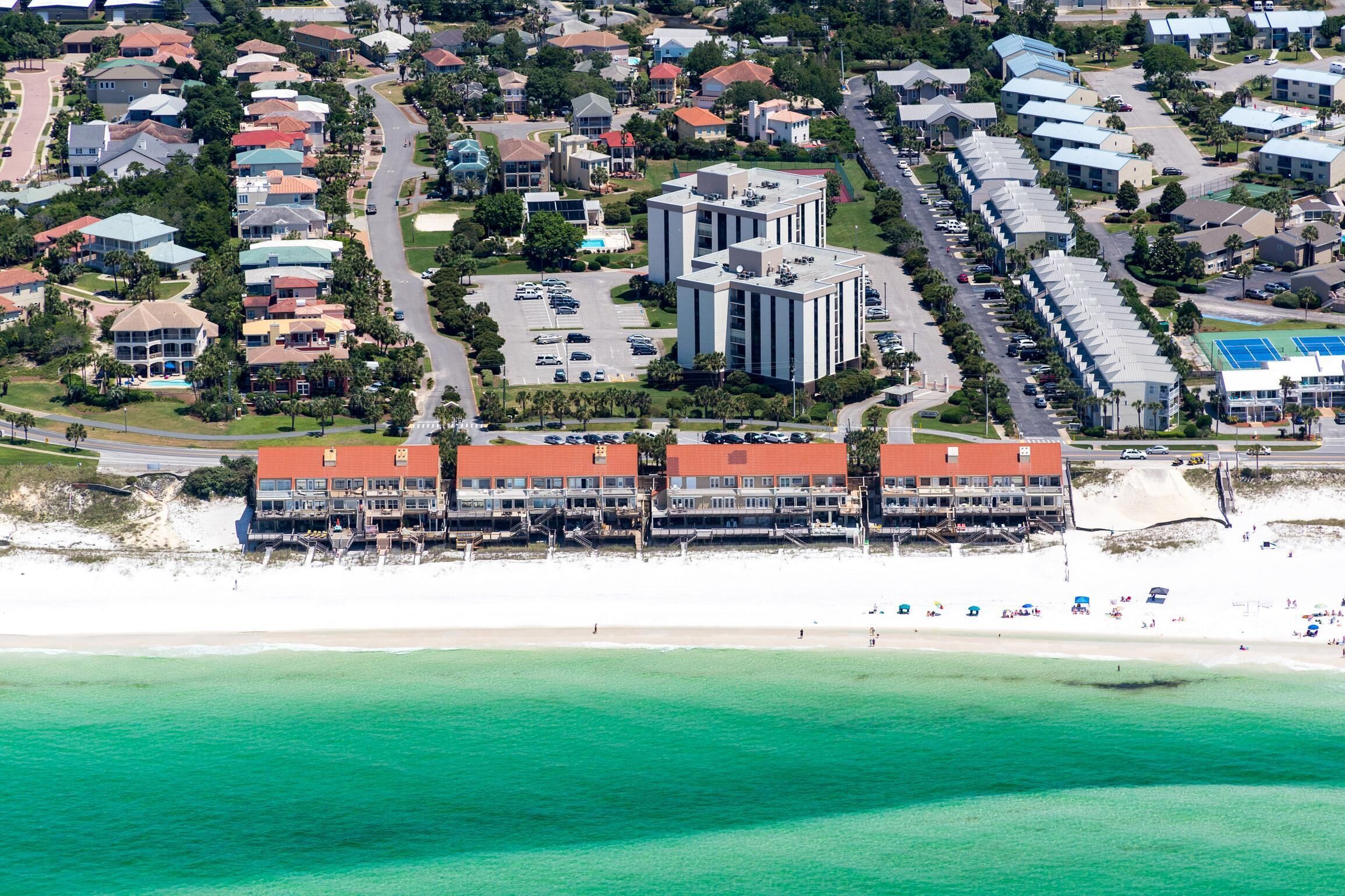 An aerial view of a coastal hotel with multiple buildings, a beach, and a parking lot.