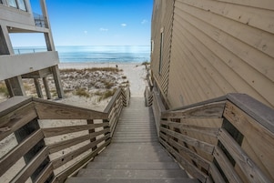 Una escalera de madera que conduce a una playa con vista despejada al océano.