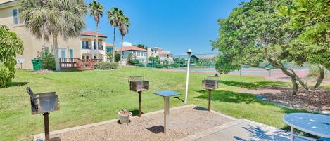 A patio area with a table and chairs, a barbecue grill, and a mailbox.