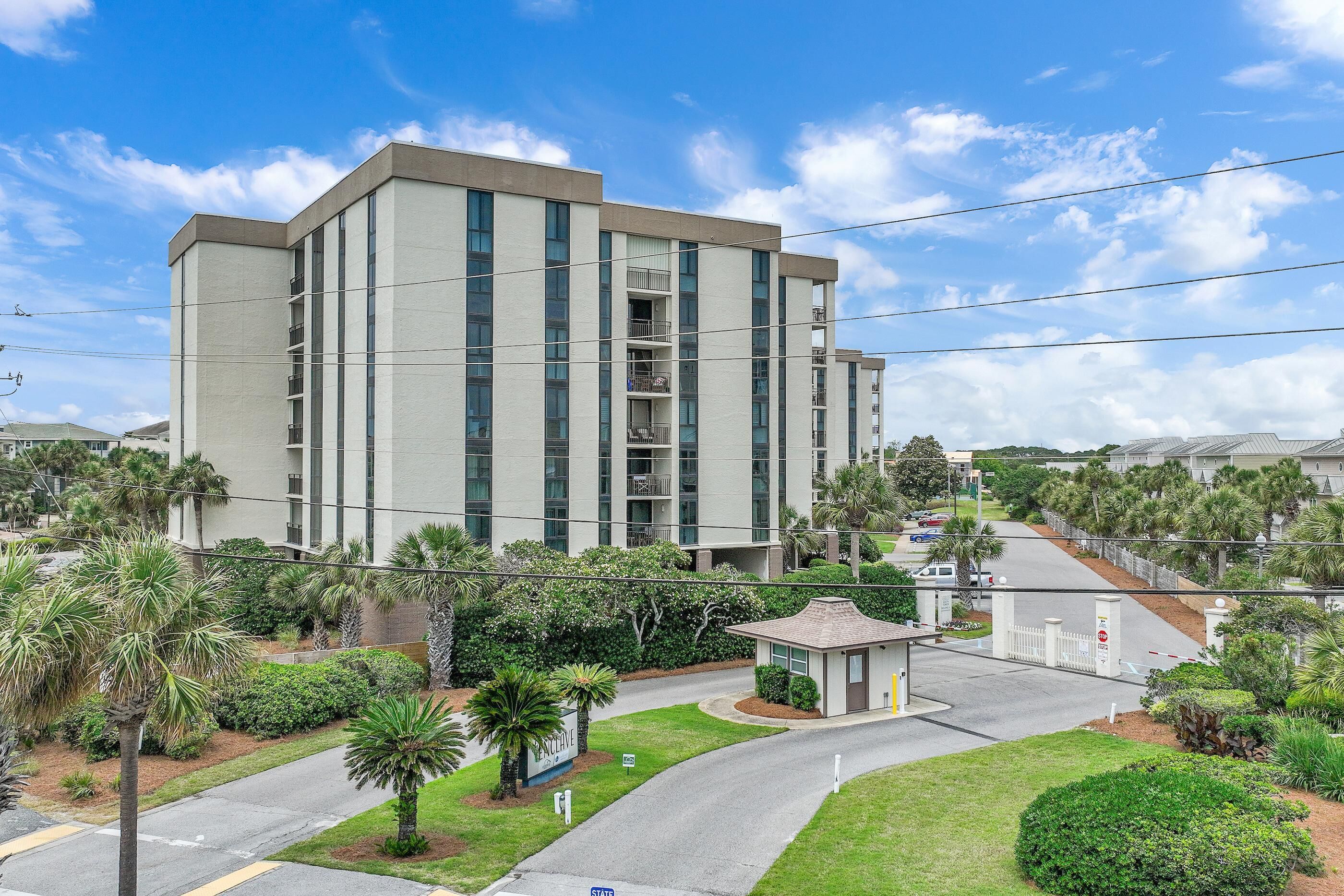 A multi-story building with a flat roof, surrounded by well-maintained greenery and a clear sky.