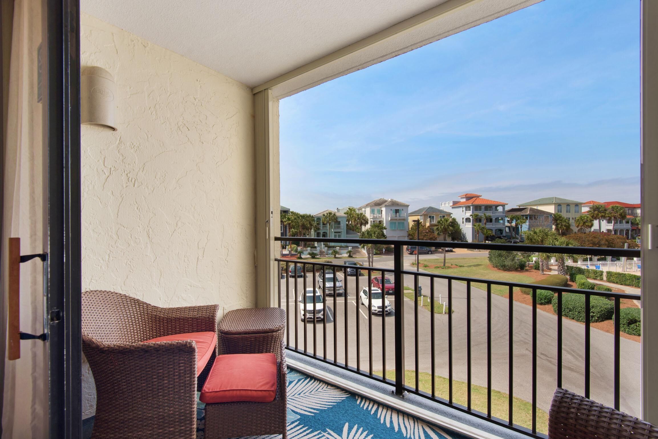 A balcony with wicker furniture and a view of a residential area.