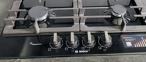 Boschin kaasuliesi, jossa on neljä poltinta ja ohjauspaneeli, jossa on merkintä «FlameSelect».