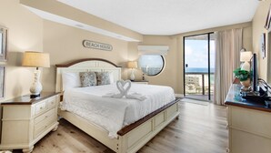 A hotel room with a large bed, a view of the beach, and a sign that reads "BEACH HOUSE". - Surfside Resort #505 (Miramar Beach)