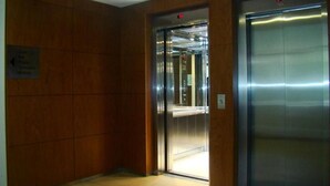 An elevator with a metallic finish and a red emergency light.