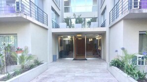 A modern building with a central entrance, glass doors, and a tiled floor.