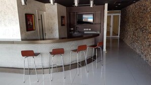 A bar area with a curved counter and four red bar stools.