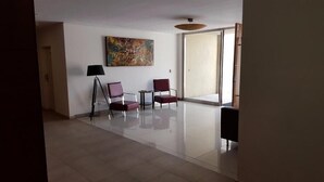 A spacious room with a large window, a floor lamp, and two chairs.