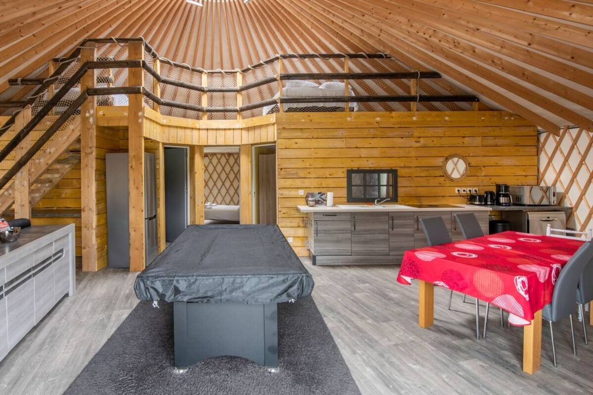 A cozy, wooden interior with a bed, a dining table, and a kitchen area.