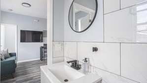 Une salle de bain moderne avec un lavabo blanc, un robinet noir et un miroir.