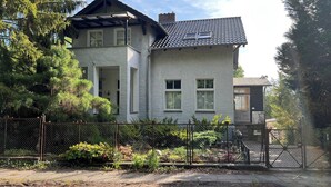 Una casa de dues plantes amb teulada inclinada, pati tancat i una petita zona de jardí.