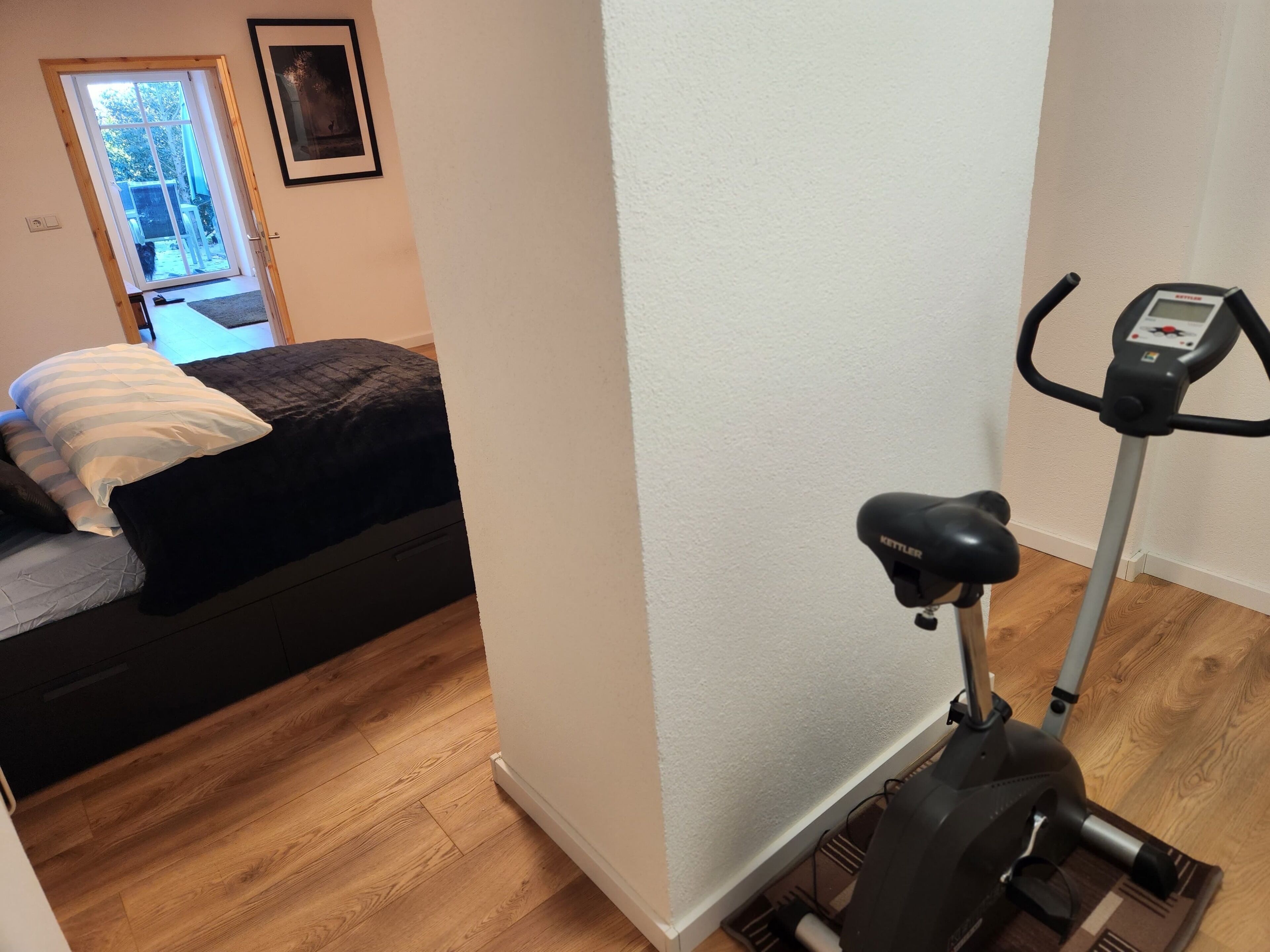A bedroom with a bed, a window, and an exercise bike.