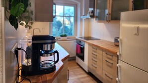Una cuina moderna amb cafetera, armaris de fusta i una finestra amb vista a arbres.
