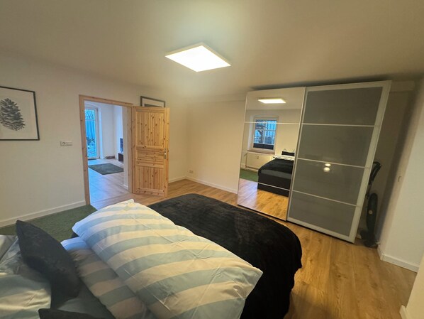 A bedroom with a bed, a wardrobe, a door, and a window.