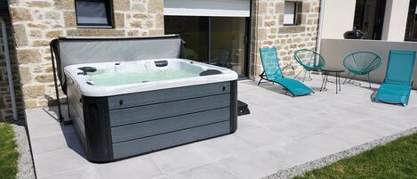 Une maison en pierre dotée d’un jacuzzi, d’un espace salon extérieur et d’une terrasse.